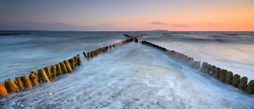Sunset at the beach of the Baltic Sea, crossing groynes, on the horizon Hiddensee, island R&uuml;gen, Mecklenburg-Western Pomerania, Germany, Europe
