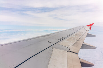 Fototapeta premium View from the airplane window at a beautiful cloudy sky and the airplane wing