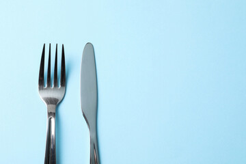 Stylish silver cutlery on light blue background, top view. Space for text