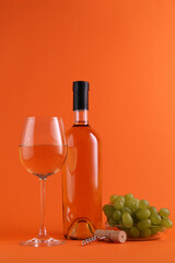 Wine, corkscrew and fresh grapes on orange background