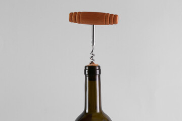 Wine bottle with corkscrew on grey background