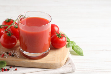 Tasty tomato juice in glass with fresh vegetables and spices on white wooden table, space for text