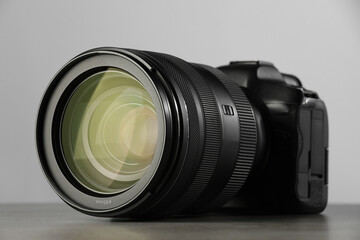 Modern photo camera on grey table, closeup. Photographer's equipment