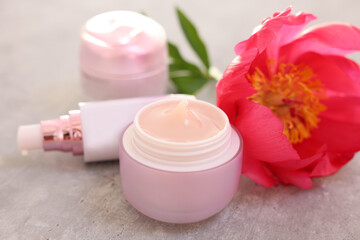 Set of different cosmetic products and peony flower on gray table, closeup