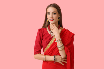 Beautiful young happy Indian woman in stylish sari on pink background