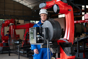 a young male caucasian technician in safety uniform checking and  maintenance welding robot machine in robot factory