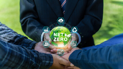 Net zero and carbon neutral concept. Businessman group joins hands around a green Earth,...