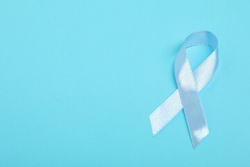 Light blue ribbon on color background, top view with space for text. Prostate cancer awareness