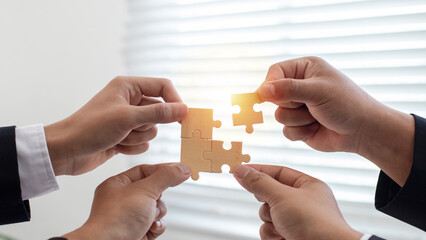 Concept of teamwork and partnership. Business people join puzzle pieces in office. Problem-solving,...
