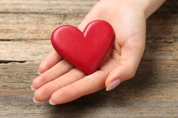 Obraz premium Woman with red decorative heart at wooden table, closeup