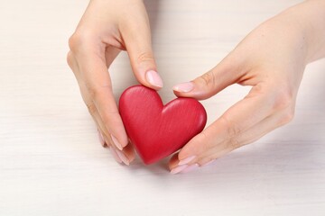 Woman with red decorative heart at white wooden table, closeup
