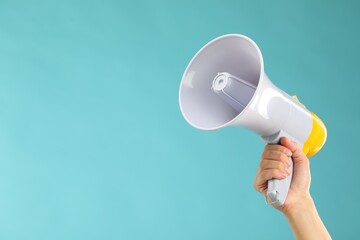 Woman holding megaphone speaker on blue background, closeup. Space for text