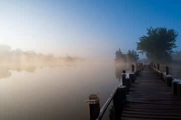 Wooden bridge across the canal, morning atmosphere with fog