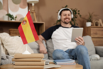 Spanish flag with books on table of man learning language online at home, closeup