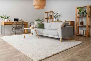 Interior of living room with sofa, workplace and aroma spray on table
