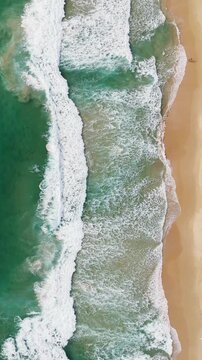 Phuket Thailand tropical beach Aerial drone top down view bird eye view of sea blue waves break on sand. Beautiful of sea water wave rip current reverse current undertow drone filming 4k vertical.