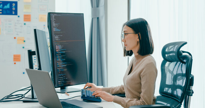 Young adult Asia female freelance eyeglasses typing write prompt AI bot IT app smart program nomad, video game, terminal with coding, user interface, designer, big data center on desktop computer.