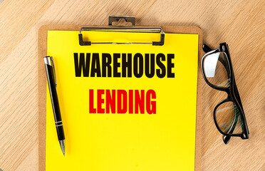 WAREHOUSE LENDING text on yellow paper on clipboard with pen and glasses