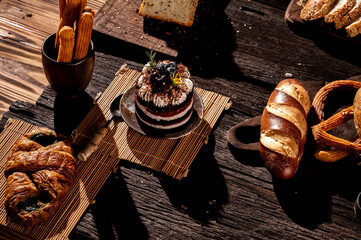 A delicious chocolate nut cake on a white plate surrounded by various pastries and a cup of coffee, perfect for breakfast or dessert