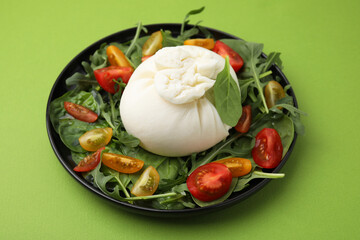 Delicious burrata salad on green table, closeup