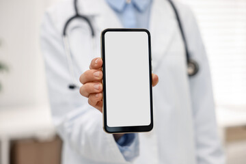 Doctor showing smartphone with blank screen in hospital, selective focus