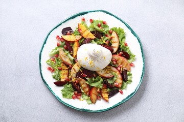 Plate with fresh burrata salad on grey textured table, top view