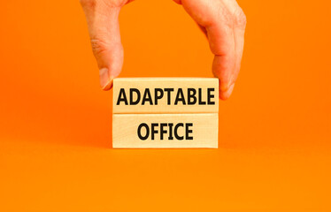 Adaptable office symbol. Concept words Adaptable office on beautiful wooden block. Beautiful orange paper background. Businessman hand. Business Adaptable office concept. Copy space.