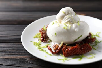 Delicious burrata cheese and sun-dried tomatoes on wooden table, closeup