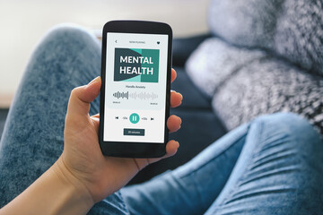 Girl on a sofa holding a smartphone displaying a meditation app. Mental health app concept.