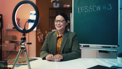 Mature Asian female teacher recording video lesson for social networks or blog