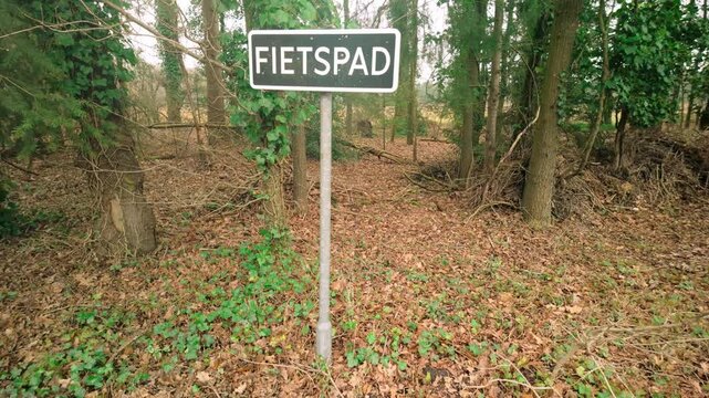 Cycle path traffic sign (Fietspad) located in a forest in the Netherlands. The sign marks a designated bike path amidst a wooded area, surrounded by trees and ground foliage. Location: Netherlands