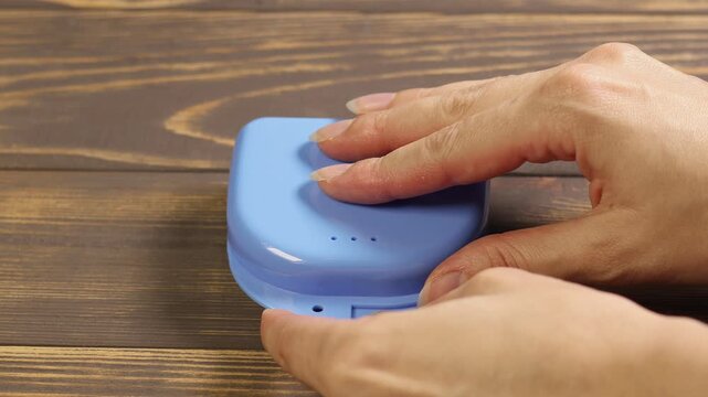 Woman takes Dental splint mouth guard from the box. TMJ splint disorder treatment. Occlusal splint. Prevent bruxism. Mouth guard for TMJ. Teeth protection. Pain in jaw. Teeth grinding.