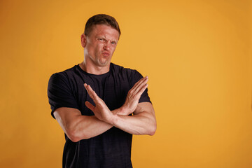 Hard dislike, showing stop or no by the hands. Man is against background in the studio