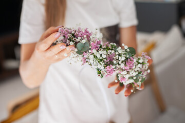 hands and flowers closeup making a handmade diy rustic boho floral wreath at masterclass of hobby class lesson, leisure creative activity. Florist crafting workshop.
