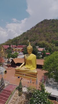 Big Gold Buddha nestled in the mountains with this stunning aerial drone footage. Soar over lush green landscapes of this magnificent statue set against a breathtaking natural. 