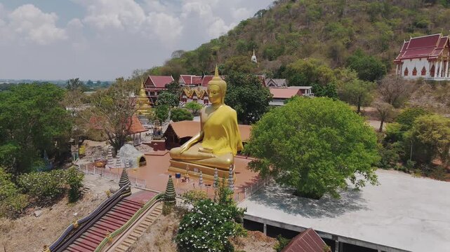 Big Gold Buddha nestled in the mountains with this stunning aerial drone footage. Soar over lush green landscapes of this magnificent statue set against a breathtaking natural. 