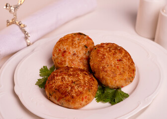 three round meat cutlets lie on a served table in a white plate, top view