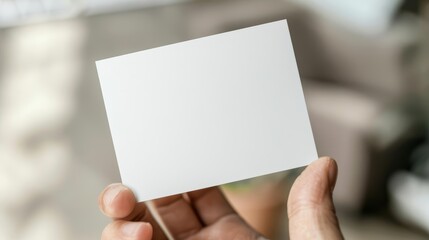 Obraz premium Blank white business card in hand, office environment, close-up, professional mockup