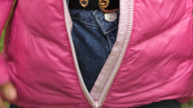 The girl unfastens the lock of her jacket