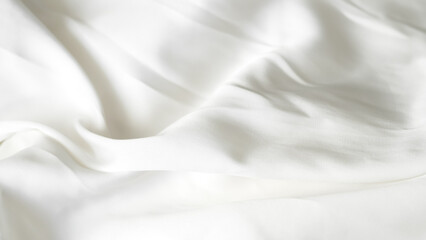 Crumpled white silk fabric background with soft folds and delicate texture.