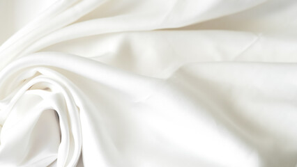 Crumpled white silk fabric background with soft folds and delicate texture.