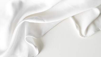 Crumpled white silk fabric background with soft folds and delicate texture.