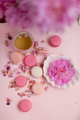 macaroon cookies, a flower on a plate and a cup of tea