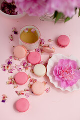 macaroon cookies with flower petals on the table and a cup of tea