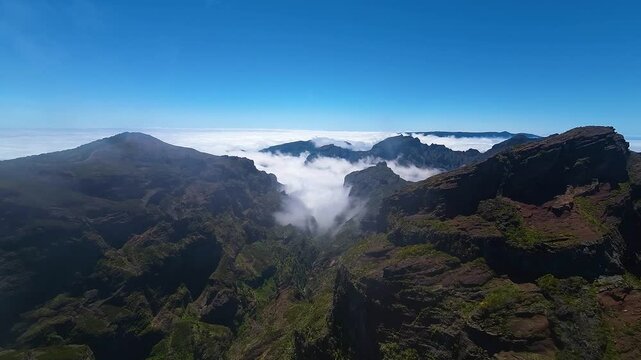 High altitude aerial view of mountain peaks, valley and clouds over stunning Madeira landscape near Pico do Pico hiking trail. Pico do Arieiro and Pico do Ruivo.