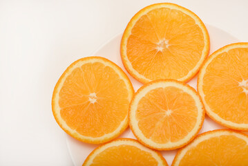 Flat slices of orange on a white plate. Chopped fruits.