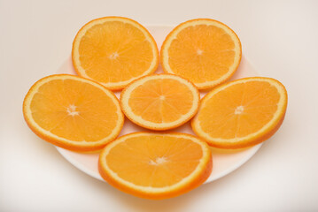 Flat slices of orange on a white plate. Chopped fruits.