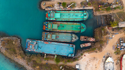 Aerial view of colorful cargo ships docked at a bustling industrial port showcasing the vibrant...