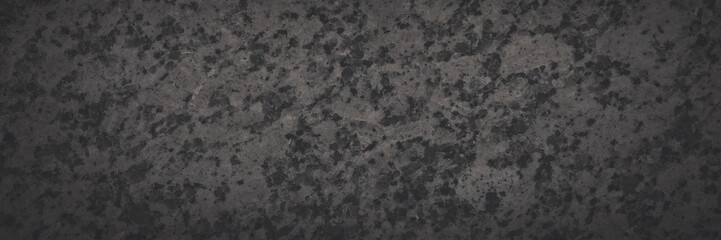 Dark gray granite texture. Natural granite with a grainy pattern. Solid rough surface of rock with spots, noise and grain. Dark stone background for design. Shaded texture with vignette.