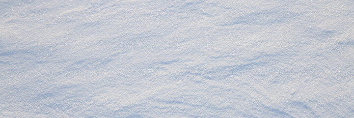 Beautiful winter background with snowy ground. Natural snow texture. Wind sculpted patterns on snow surface. Wide panoramic texture for background and design.
